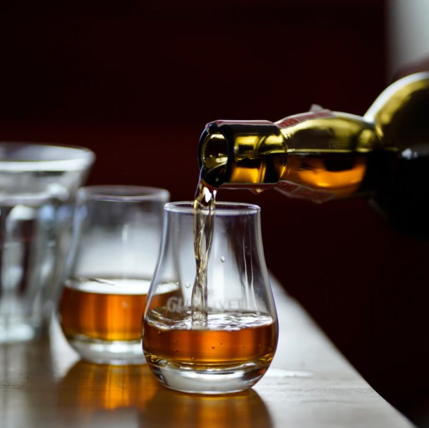 Bottle pouring whisky into glasses