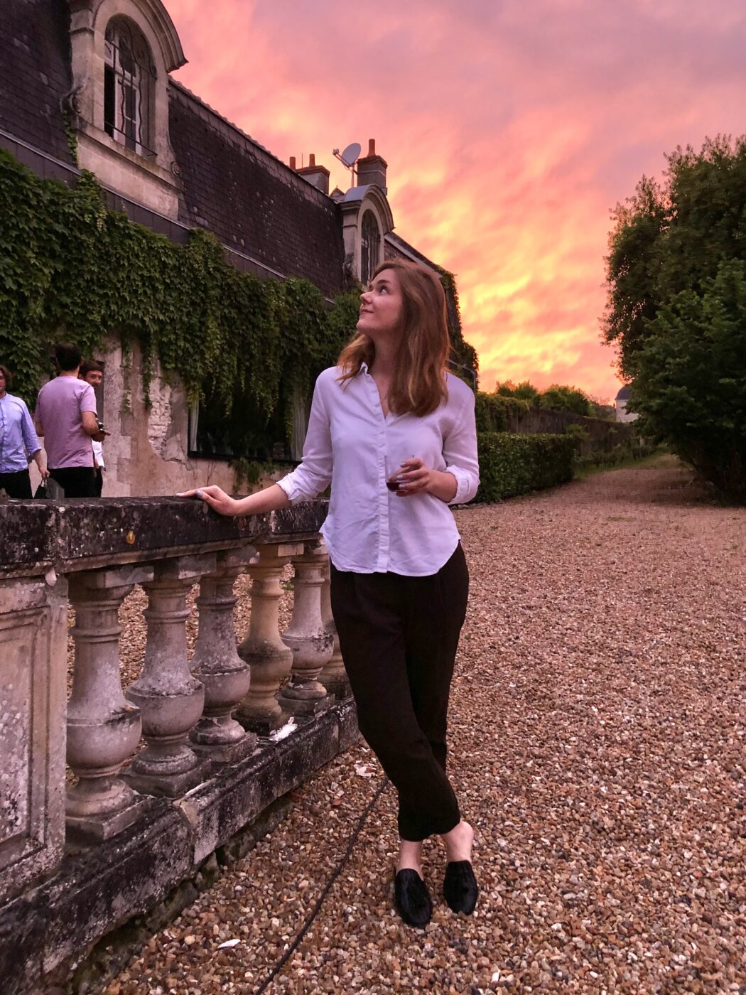 Woman standing by an old winery with a pink sky