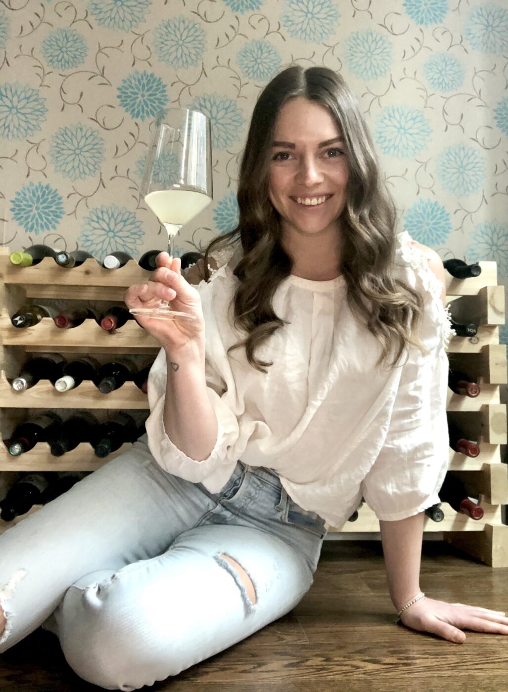 Woman sitting on a table smiling with a glass of wine in her hand