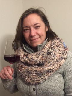 Woman smiling in a big scarf holding a glass of red wine