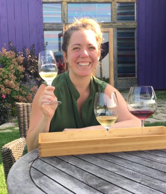 Woman smiling and sitting outside a wine with a flight of three wines