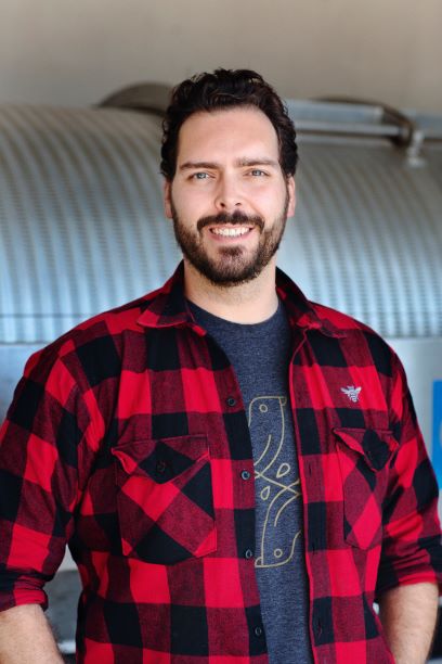 Man with a beard smiling in a red checkered shirt