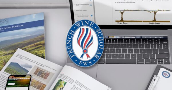 Image of logo with the words French Wine Scholar (FWS). In the background in a laptop with the image single and double guyot pruning system, the French Wine Scholar manual and a smartphone with Champagne flashcards.