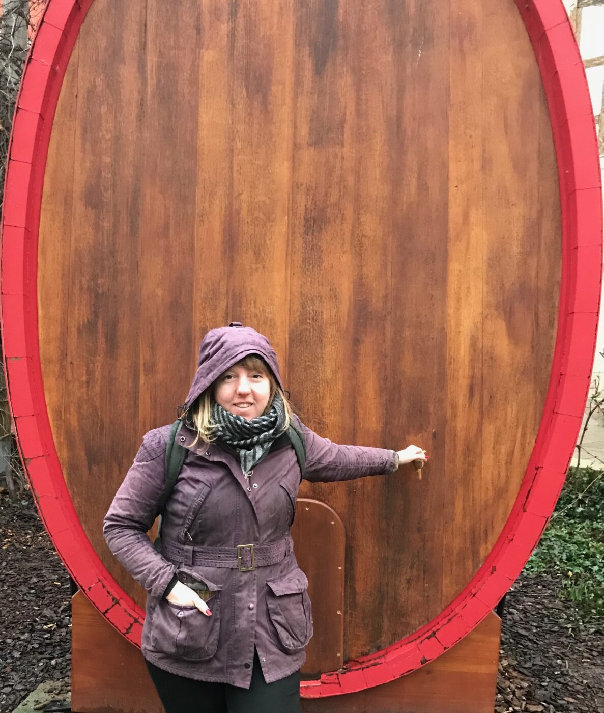 Woman smiling while standing with her hood up in front of a foudre.