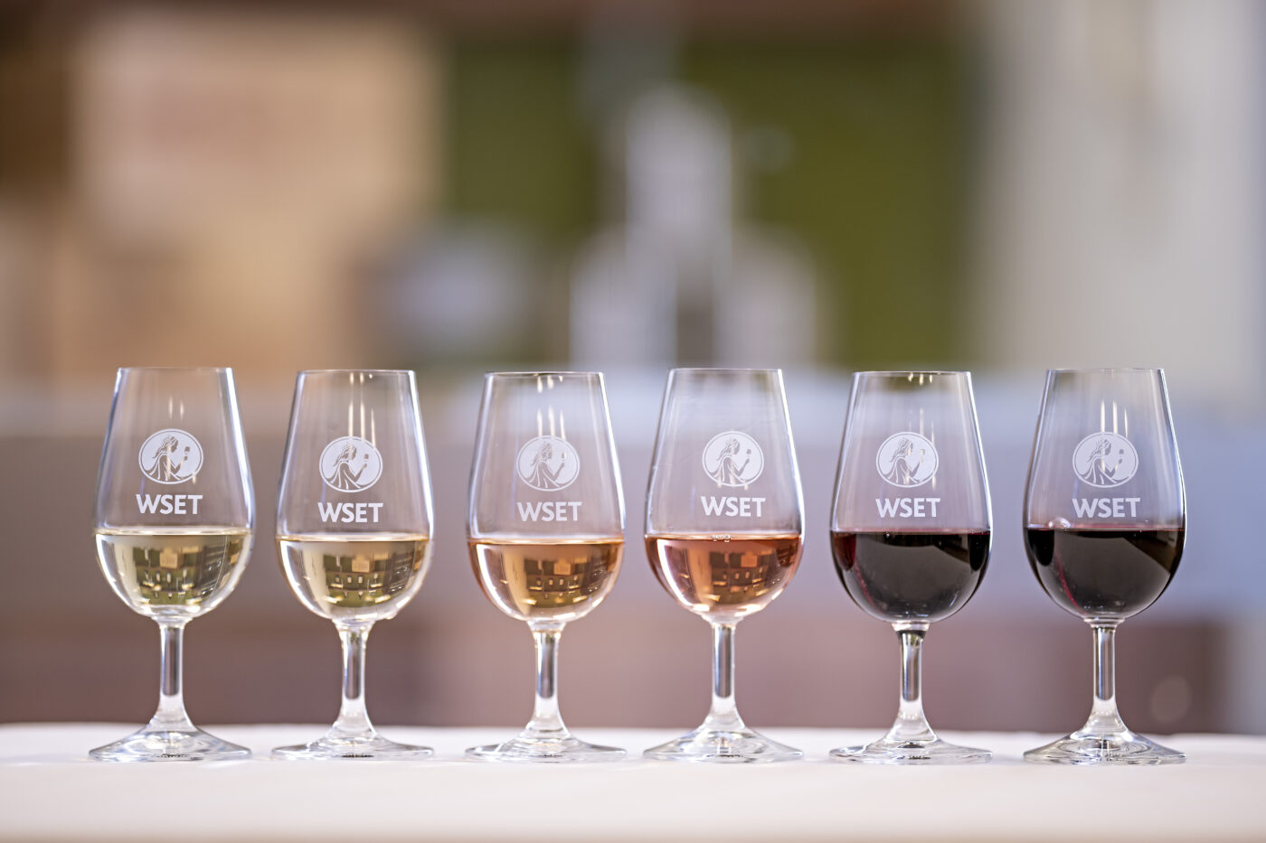 A row of 8 various types of wine from white, rose to red in glasses