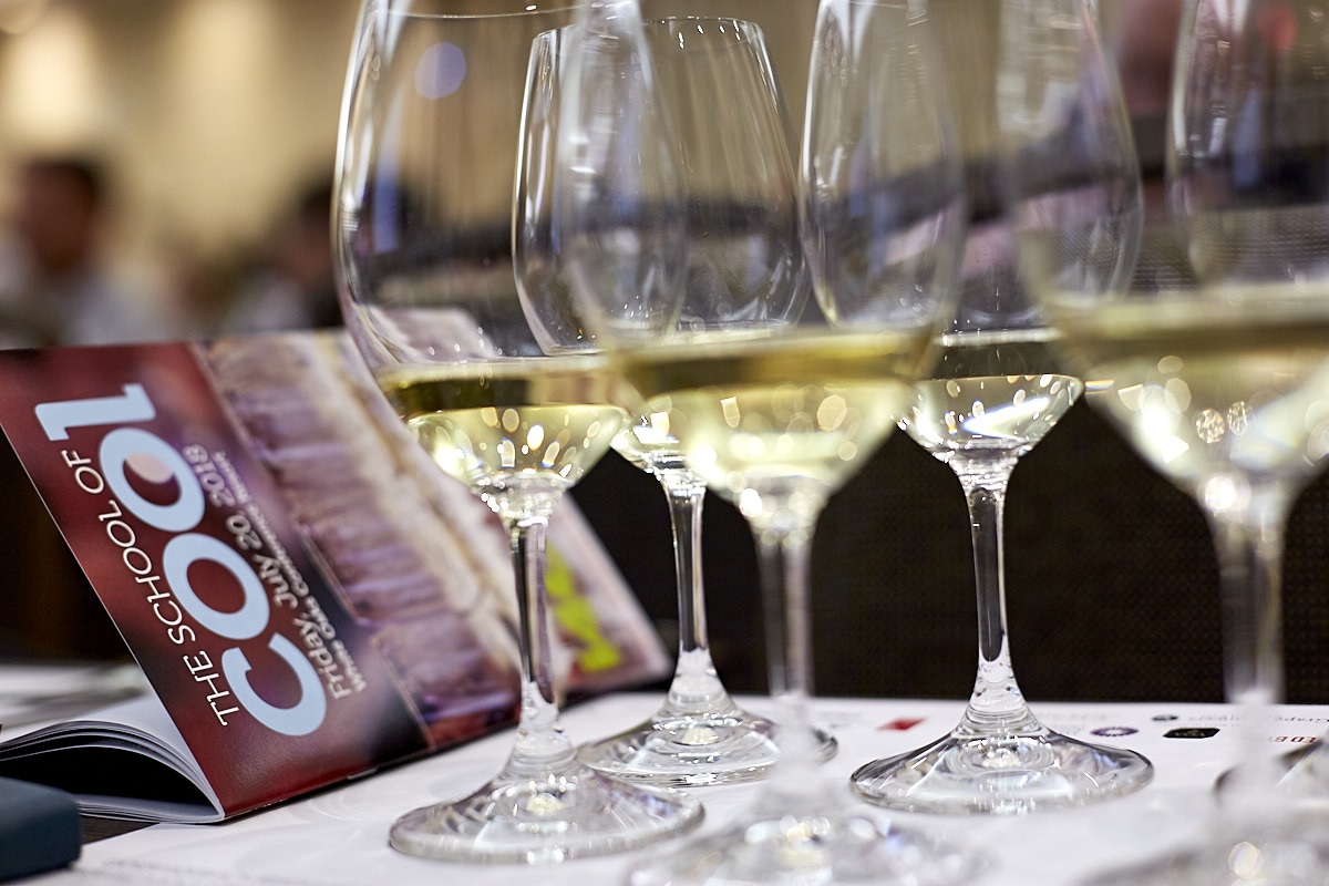 Row of glasses of chardonnay wine with a red booklet that says school of cool.