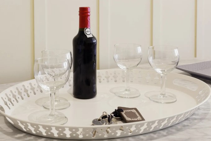 Bottle of port wine on a white tray with four glasses and keys.