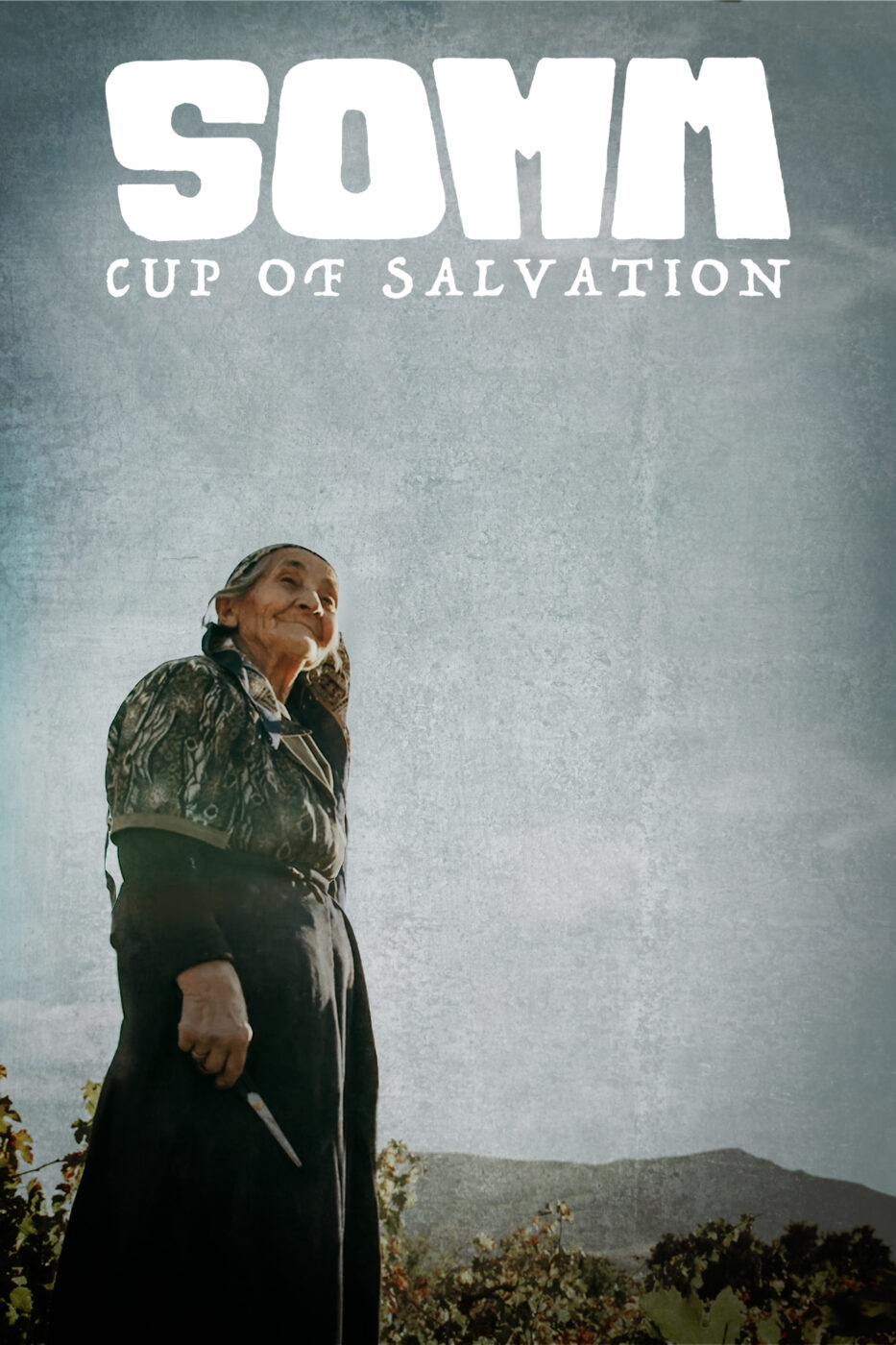 An elderly woman in a shawl smiling up at the sky with a vineyard landscape in the background. The text reads SOMM: Cup of Salvation.