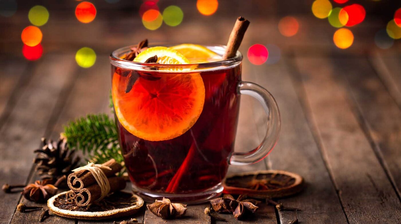 Glass mug filled with mulled white with cinnamon, orange slices and star anise. 
